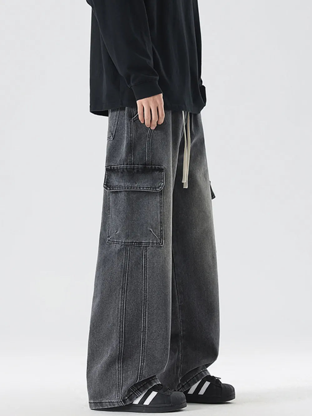 Oversized dark gray denim cargo jeans with drawstring waist and large front pockets.