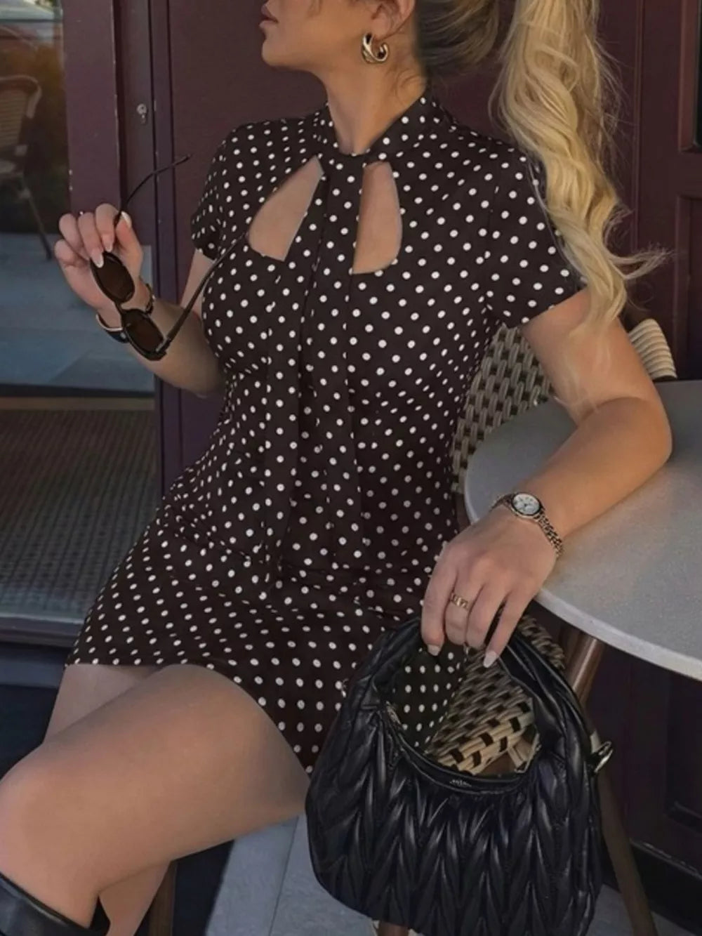 Brown polka dot mini dress with cut-out neckline and short sleeves.