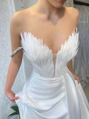 White feather embellished maxi dress with draped skirt and strapless neckline.