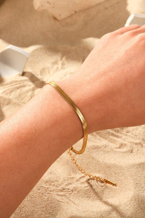 Golden serpent herringbone chain bracelet with adjustable clasp detail.