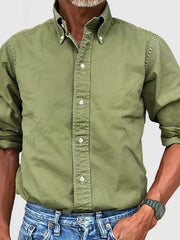 Olive green Oxford button-down shirt with relaxed fit and button collar, paired with blue jeans.
