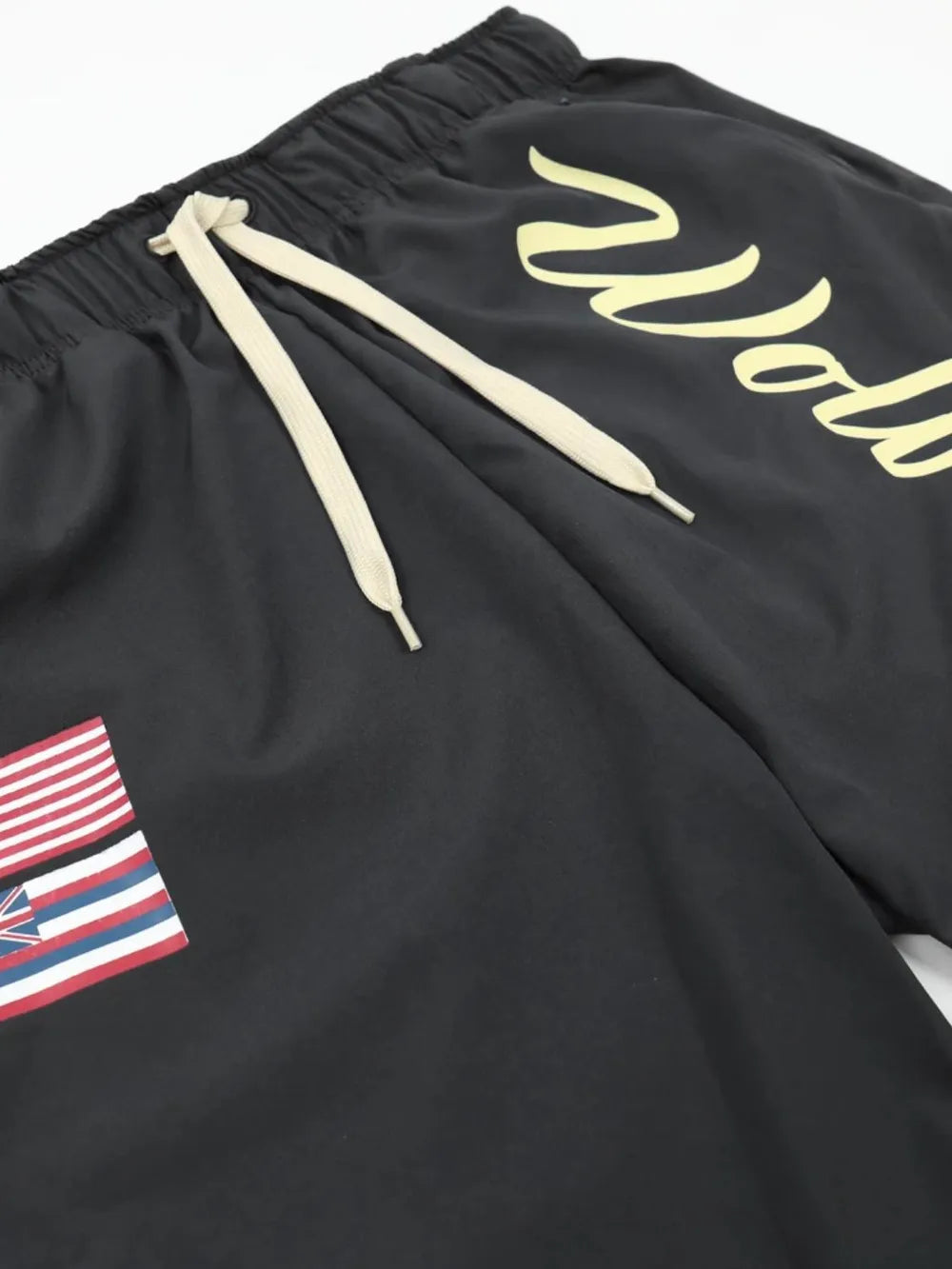 Black active shorts with drawstring and Wolves script logo, featuring a flag patch.