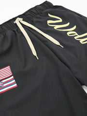 Black active shorts with drawstring and Wolves script logo, featuring a flag patch.