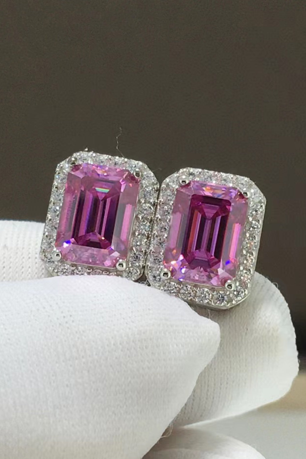 Emerald cut moissanite halo stud earrings in rose gold with pink center stones.
