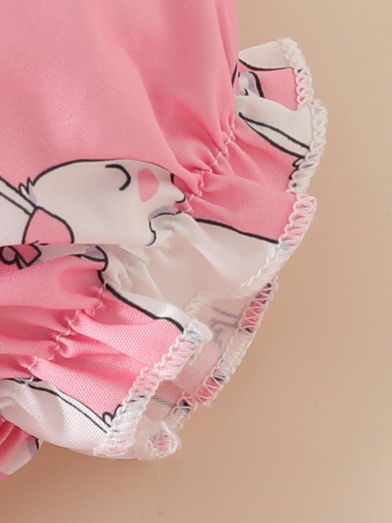 Pink baby dress with bunny print and ruffled trim.