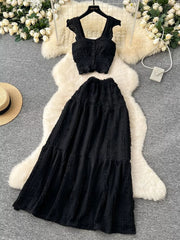 Black textured two-piece set with ruffled crop top and tiered maxi skirt.