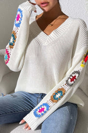 White knit sweater with colorful granny square sleeve details and V-neck.