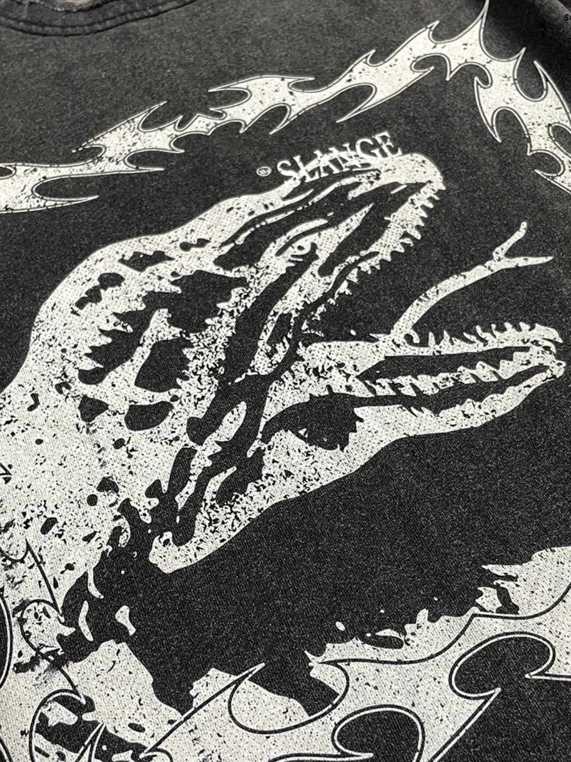 Black distressed graphic tee with a white dinosaur motif and tribal flames.