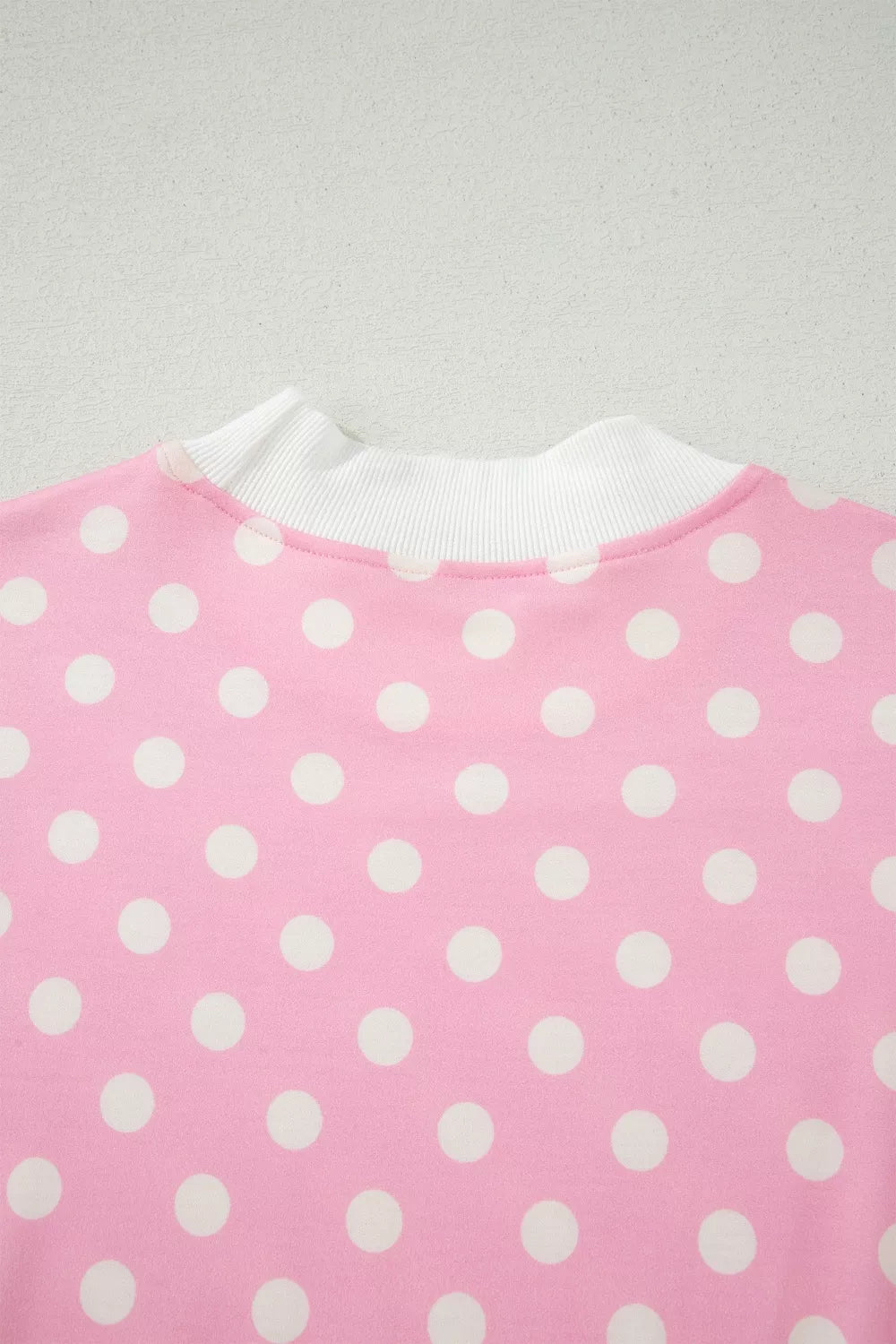 Pink polka dot top with white ribbed mock neck detail