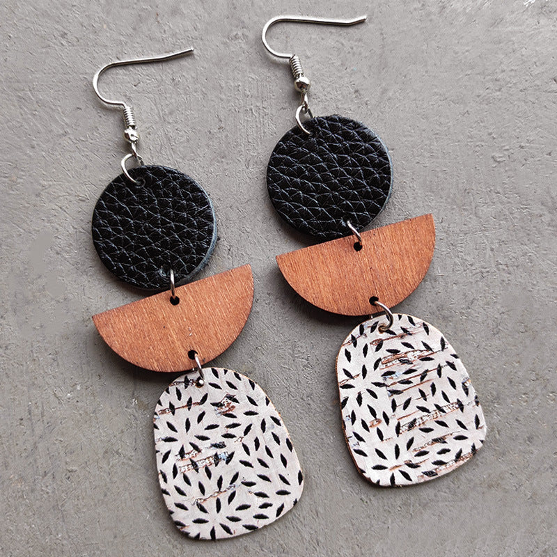Geometric layered leather and wood earrings with black, wood, and patterned cork.