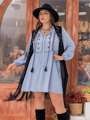 Misty blue embroidered mini dress with tassel tie neckline and long sleeves, styled with a fringed vest.