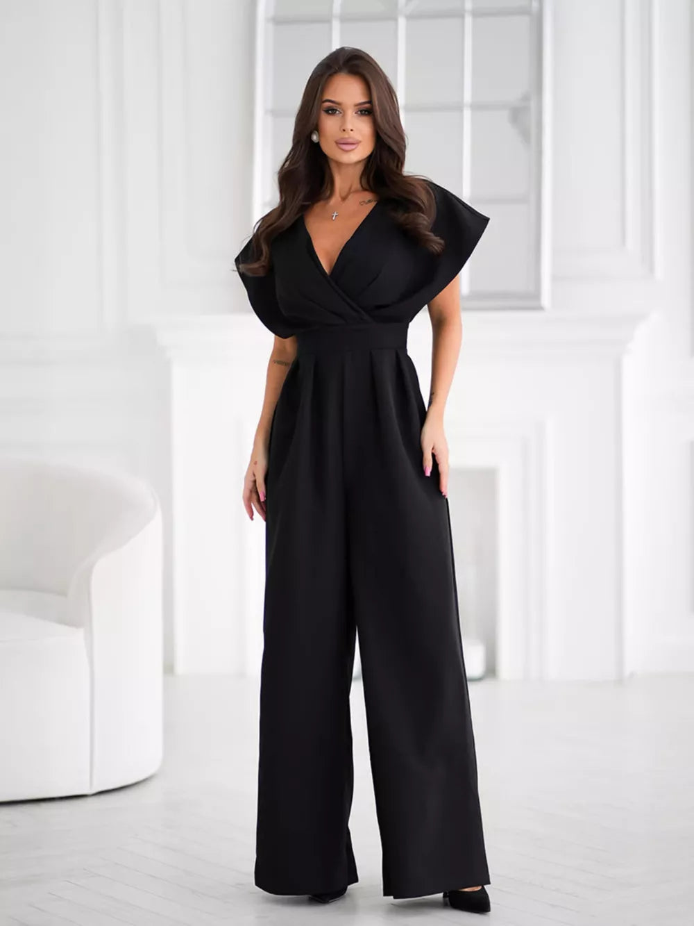 Black wide-leg romper with surplice V-neckline and flutter sleeves.
