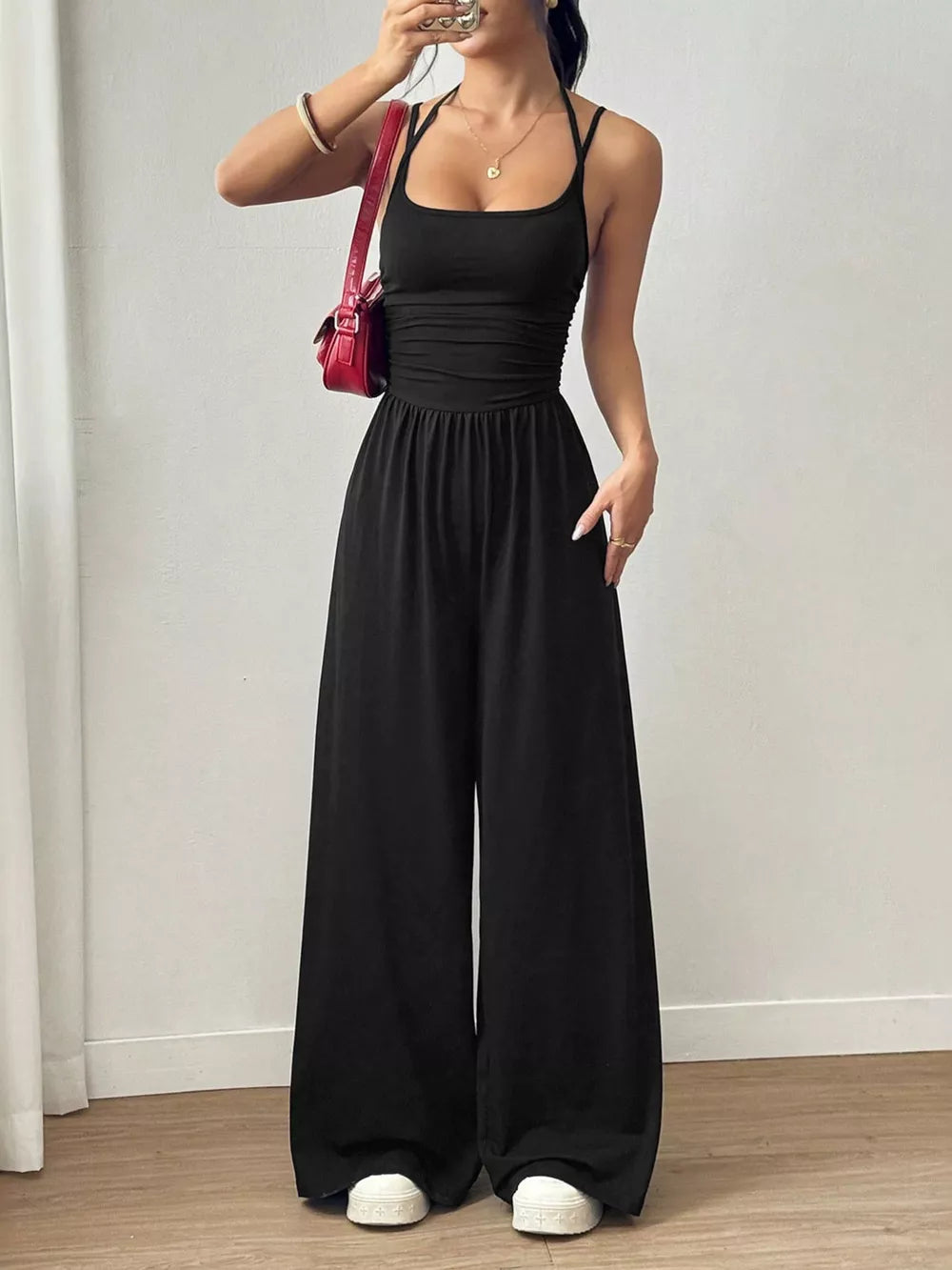 Black ruched wide-leg jumpsuit with spaghetti straps and a square neckline.