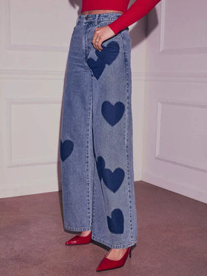 Blue denim maternity jeans with dark blue heart patches and a wide leg.