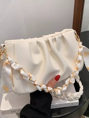 Beige ruched mini shoulder bag with braided strap and gold chain detail.