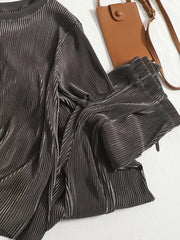 Elegant pleated two-piece set in dark gray, featuring a textured fabric and a stylish crossbody bag.