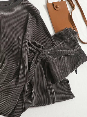Elegant pleated two-piece set in dark gray, featuring a textured fabric and a stylish crossbody bag.