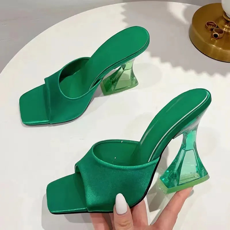 Dark green satin mules with square toe and clear sculpted heel.