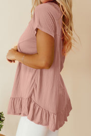 Textured peplum top in dusty pink with ruffle hem and short sleeves.