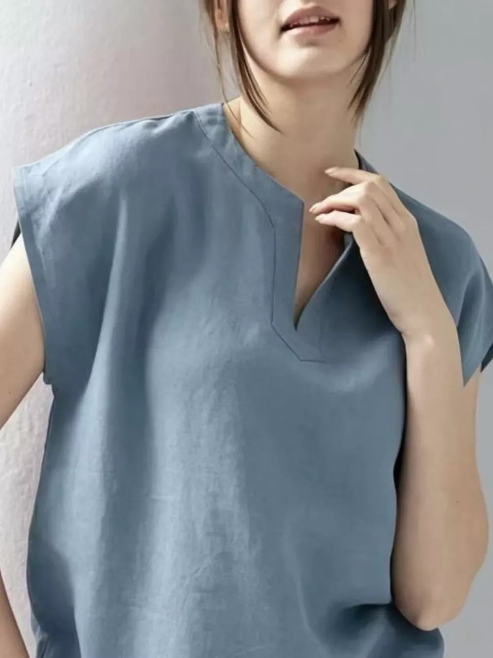 Blue cap sleeve shirt with notched neckline, relaxed fit.
