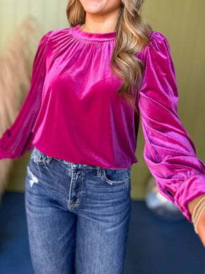 Hot pink velvet blouse with ruched neckline and puff sleeves.