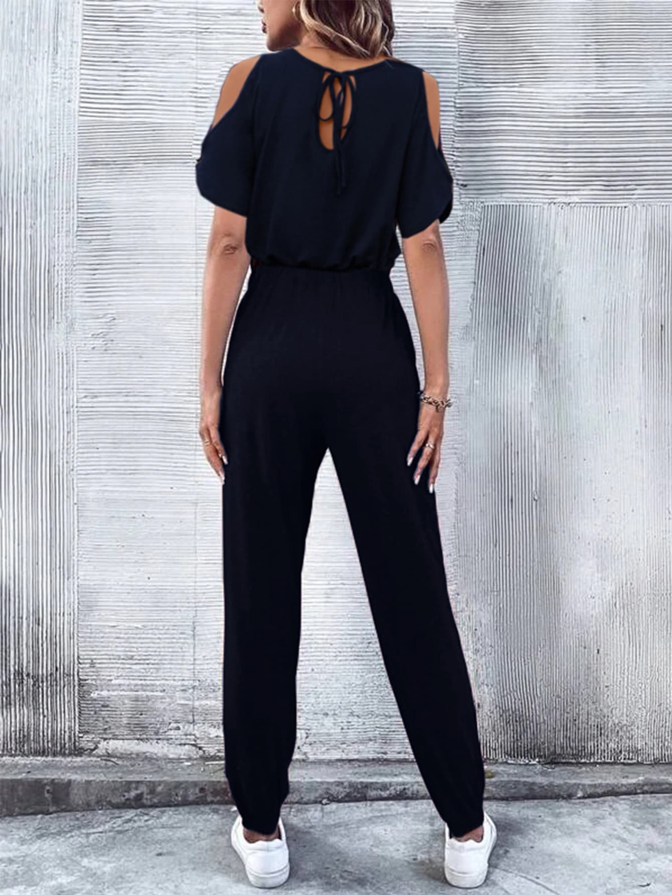 Dark blue cold-shoulder jumpsuit with drawstring waist and tie back detail.