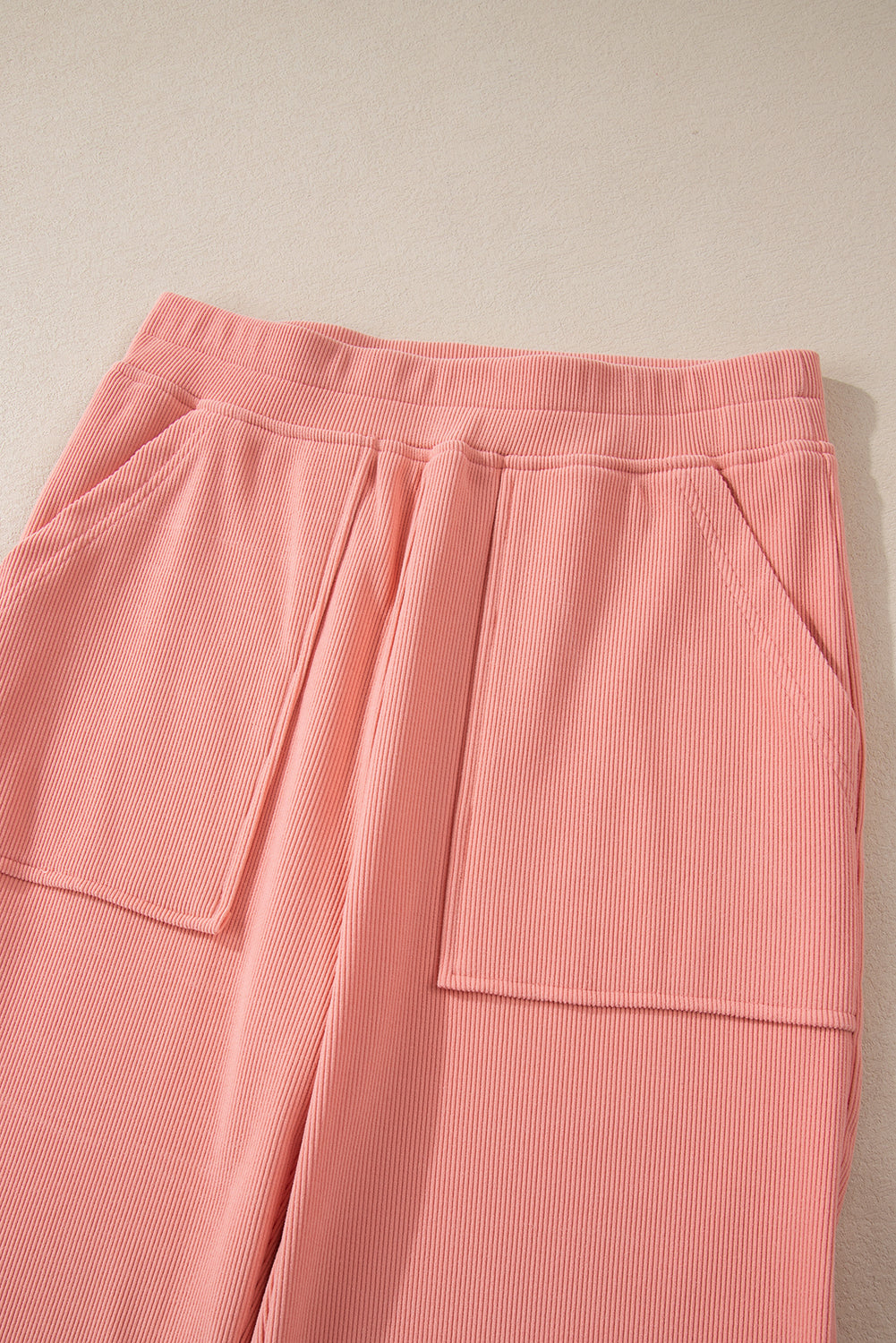 Pink corduroy lounge pants with relaxed fit and patch pockets.