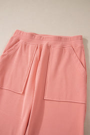 Pink corduroy lounge pants with relaxed fit and patch pockets.