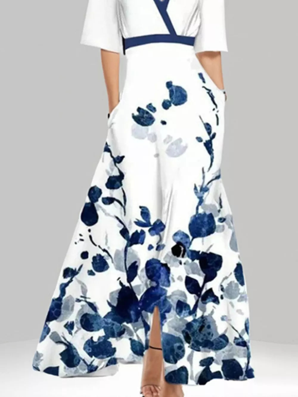 White maxi dress with blue floral print, pockets, and a defined waist.
