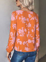Orange floral tie-neck blouse with pink flowers, long sleeves, and a relaxed fit.