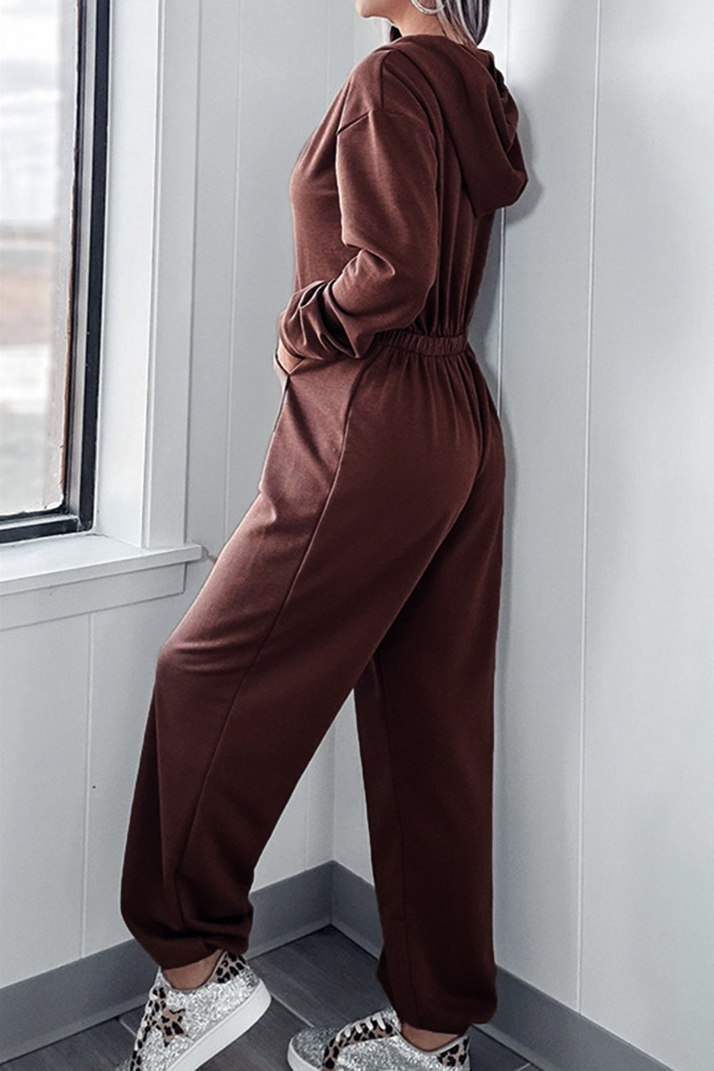 Brown hooded lounge jumpsuit with wide leg and elastic waist, shown from side.