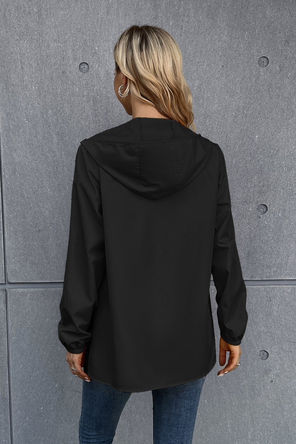 Black hooded rain coat with long sleeves and a relaxed fit.