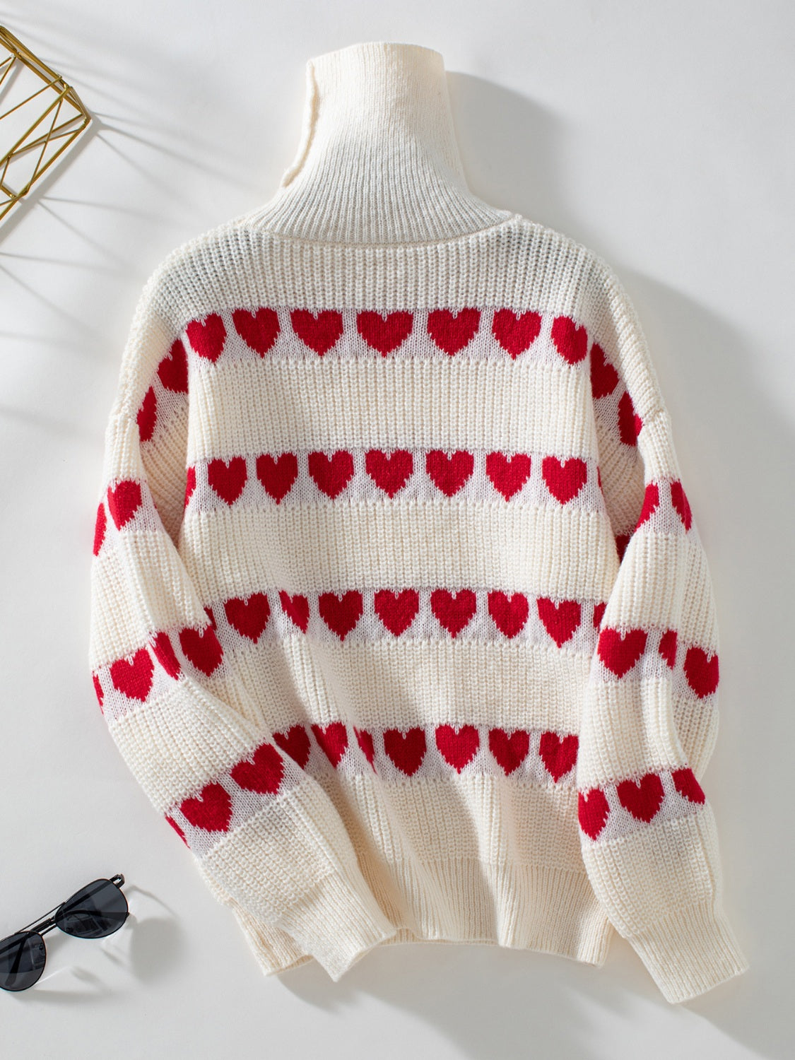 Cream turtleneck sweater with red heart intarsia pattern and ribbed knit details.