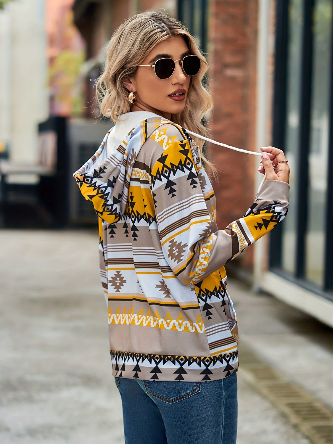 Aztec print zip-up hooded jacket with drawstring in tan, yellow, white, and black.