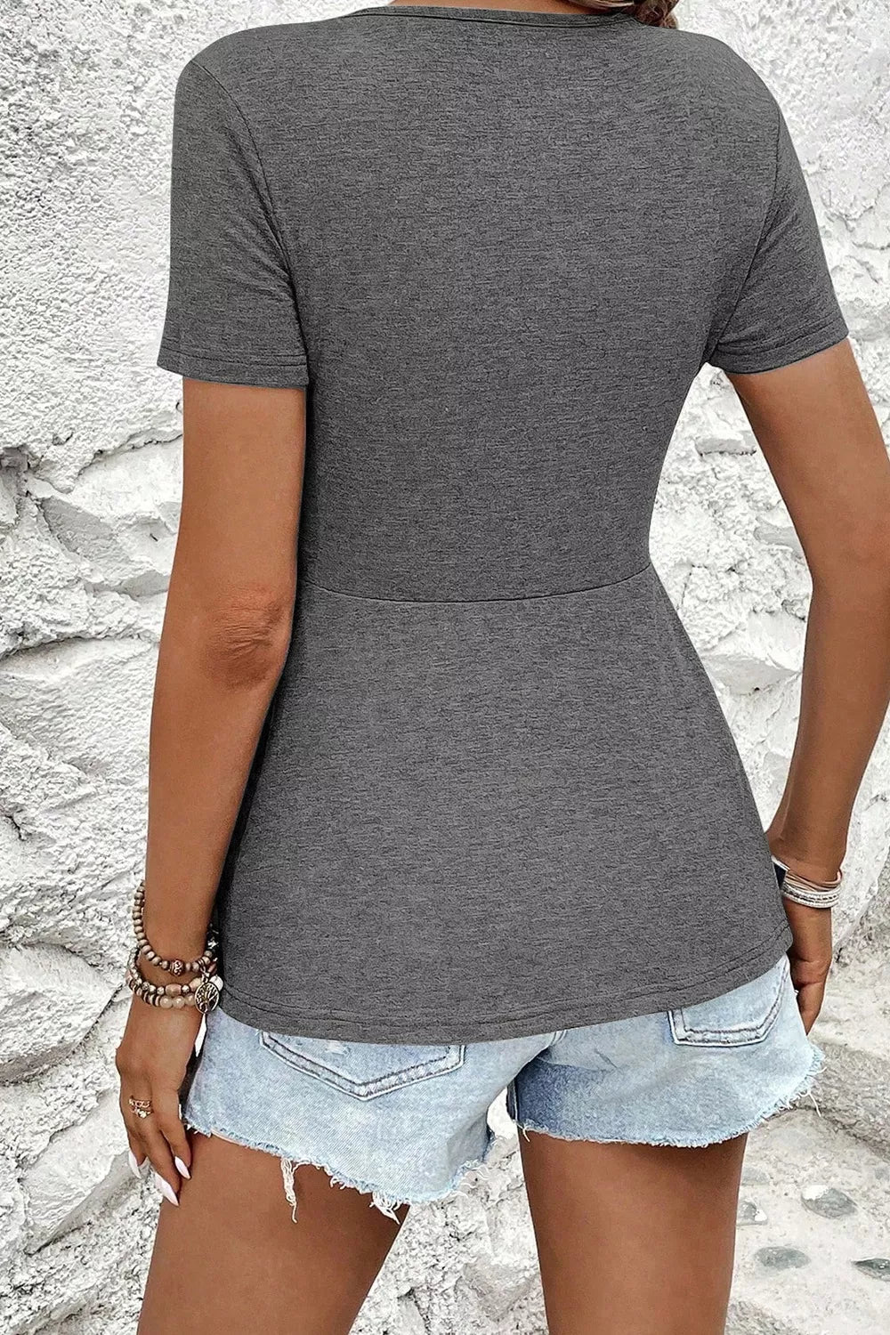 Gray polyester t-shirt with short sleeves and a peplum hem, styled with denim shorts.