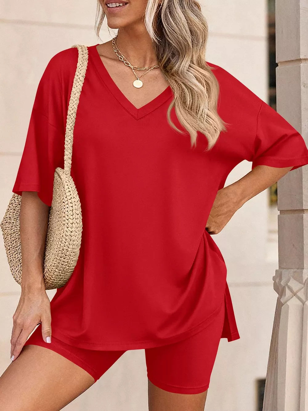 Red V-neck two-piece set with relaxed fit top and biker shorts, styled with a straw bag.