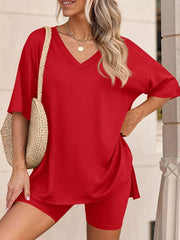 Red V-neck two-piece set with relaxed fit top and biker shorts, styled with a straw bag.
