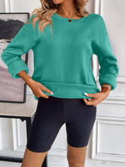 Teal relaxed fit sweatshirt with crewneck and cuffed sleeves, worn with black biker shorts.