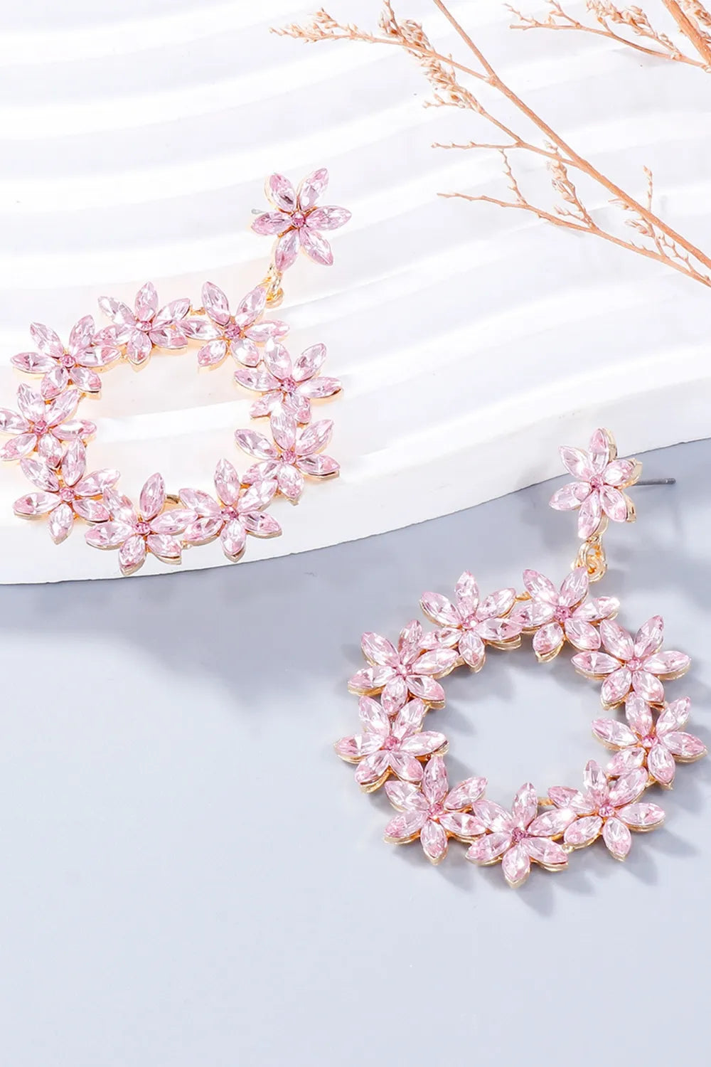 Blush pink floral halo drop earrings with crystal accents and gold tone alloy.