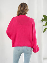 Hot pink acrylic knit cardigan with balloon sleeves and floral appliqué detail on the cuff.