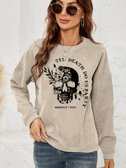Sand corduroy sweatshirt with a black floral skull graphic and text.