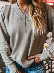 Gray V-neck sweatshirt with Aztec embroidery on sleeves and neckline detail.