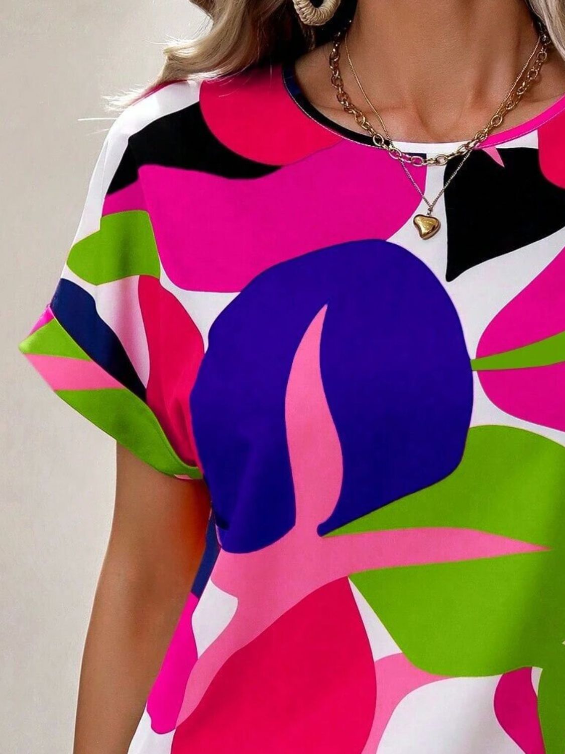 Women's abstract floral print t-shirt with short sleeves and a crew neck in vibrant pink, green, blue, and black.