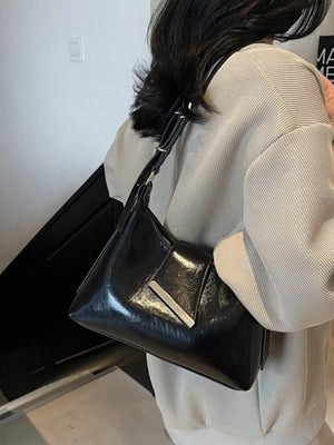 Black patent leather crossbody bag with adjustable strap and silver hardware detail.
