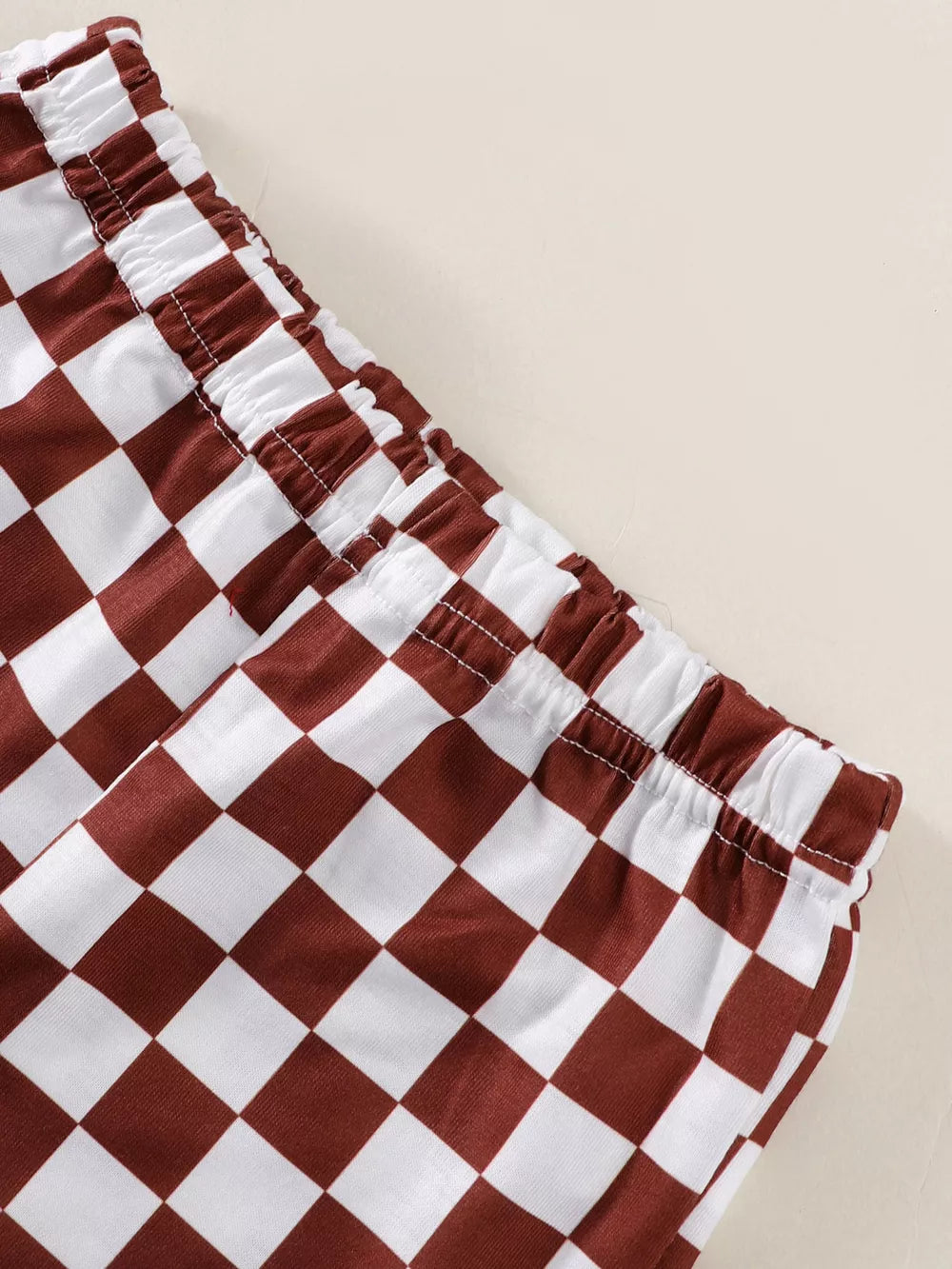 Baby shorts with brown and white checkered pattern and elastic waistband.