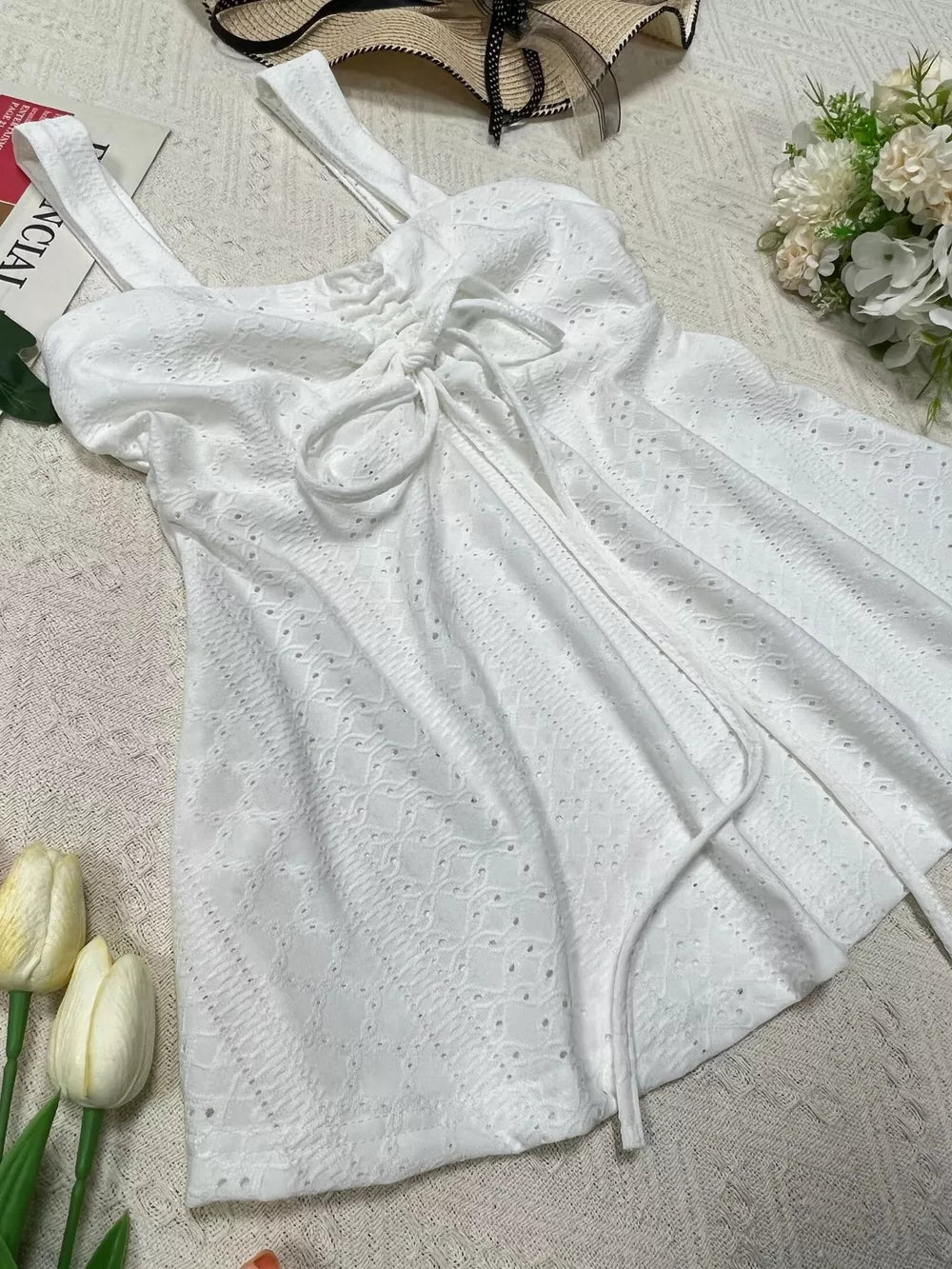 White eyelet camisole with drawstring detail and adjustable straps.