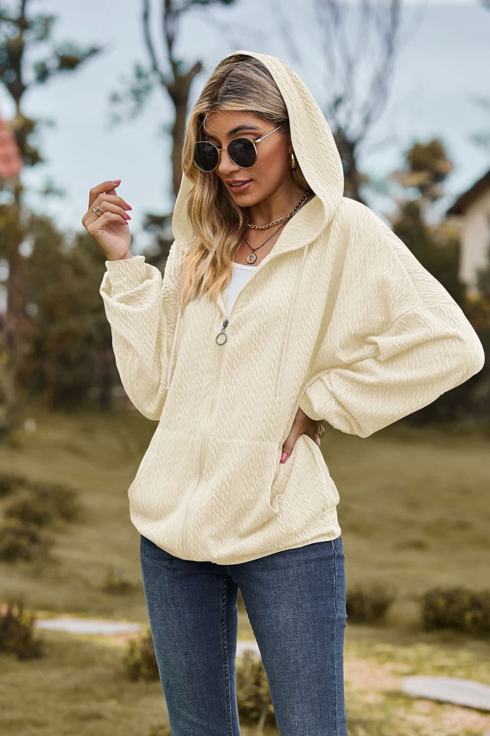 Ivory textured cable knit zip-up hoodie with pockets and a hood.