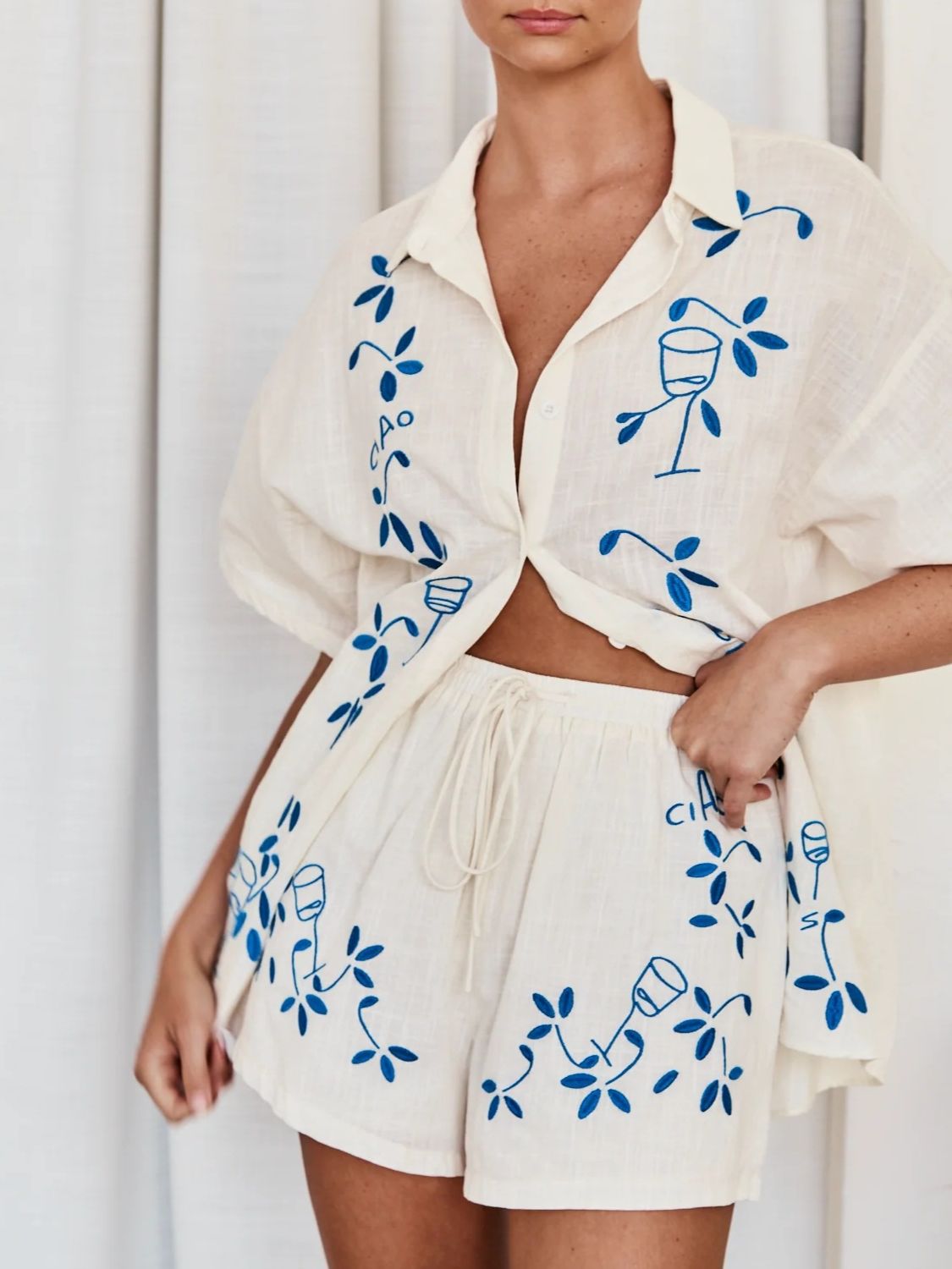 Embroidered linen co-ord set in cream with blue floral and wine glass embroidery, featuring a button-up shirt and drawstring