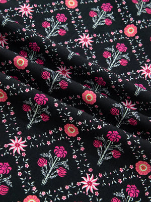 Black cotton blouse with a vintage floral print in pink and coral, featuring bracelet sleeves.