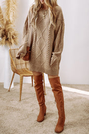 Tan cable knit sweater dress with diamond pattern, crew neck, long sleeves, and pockets.